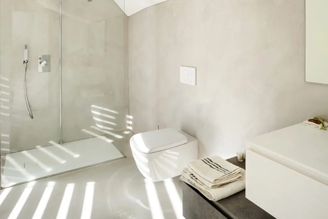 Baño con suelo y paredes de microcemento en tonalidad clara